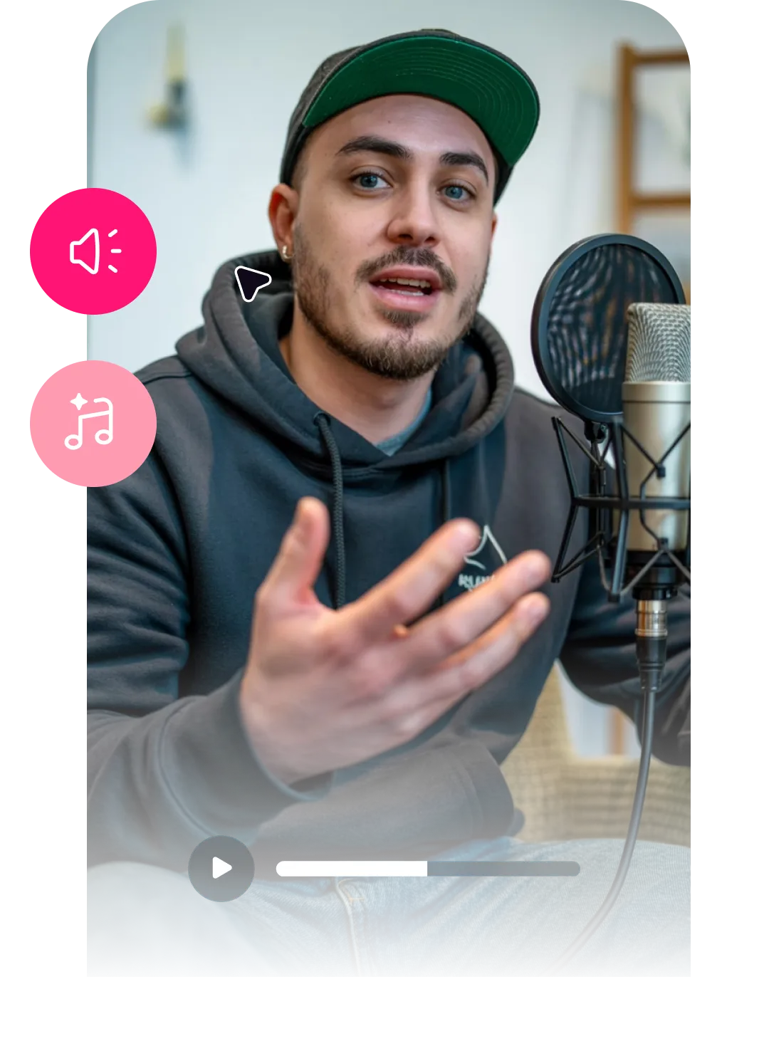 Man in gray hoodie and green cap speaking into studio microphone with audio editing icons and playback controls visible.