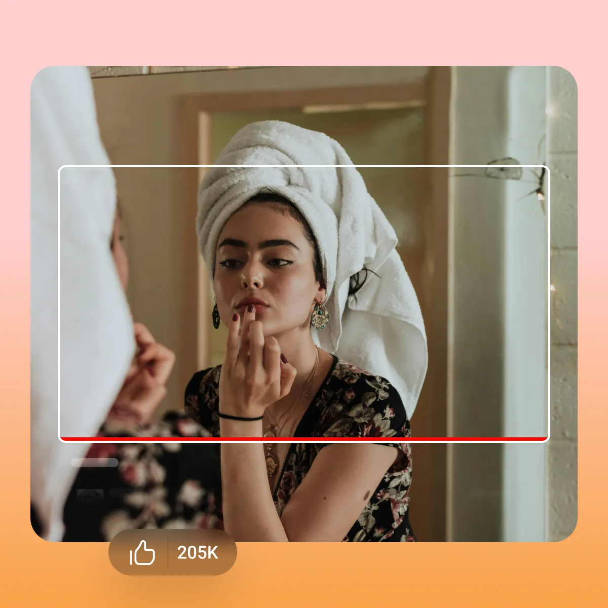 Vide thumbnail of a woman with towel wrapped on head applying makeup in a mirror. There is a horizontal video frame around with a like icon should 205k thumbs up.