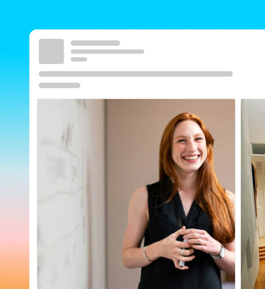 Smiling woman with long red hair wearing a black sleeveless top, holding a coffee cup in an office setting.